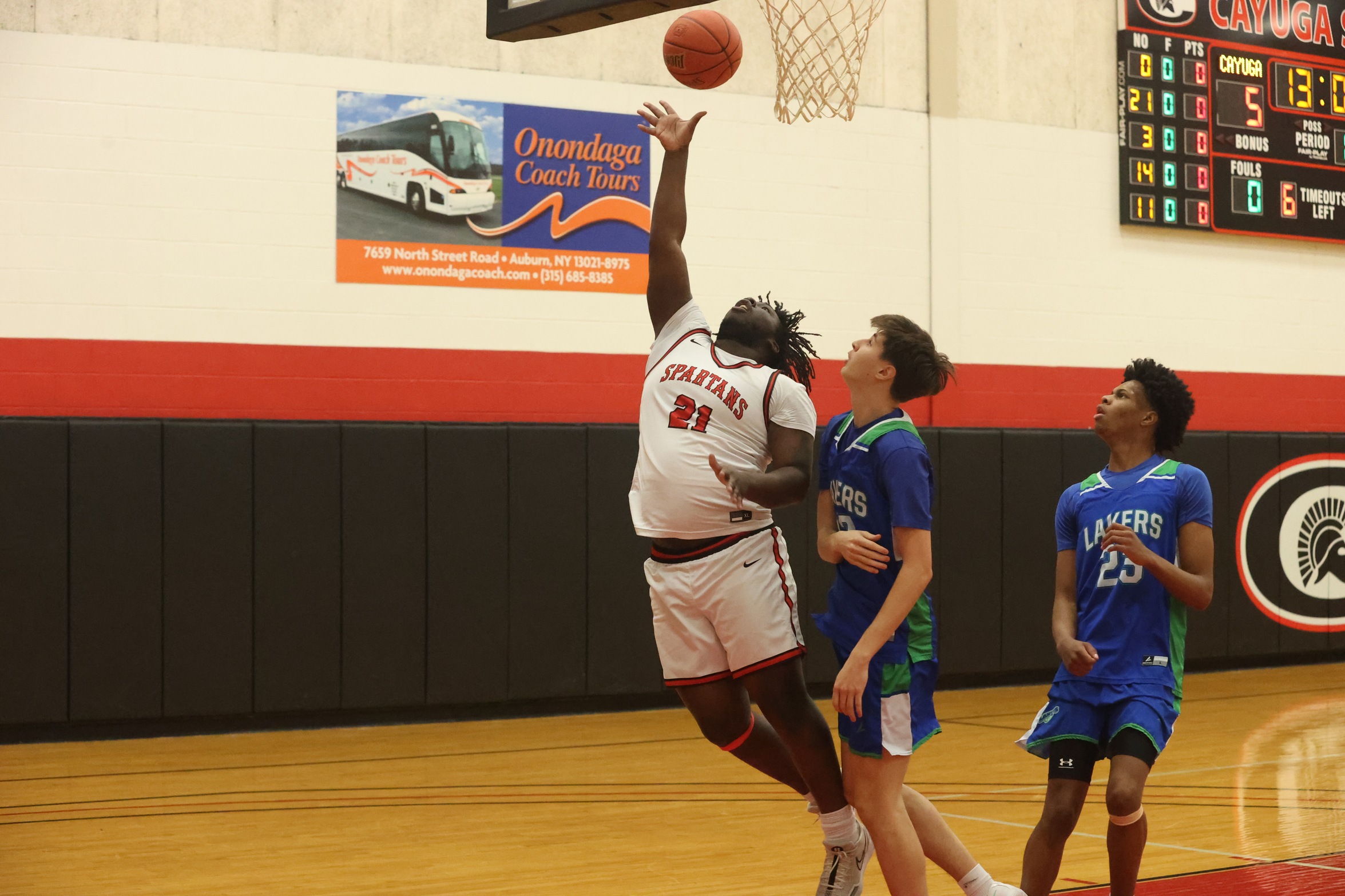 A Cayuga player shoots a layup against two Finger Lakes Community College defenders.
